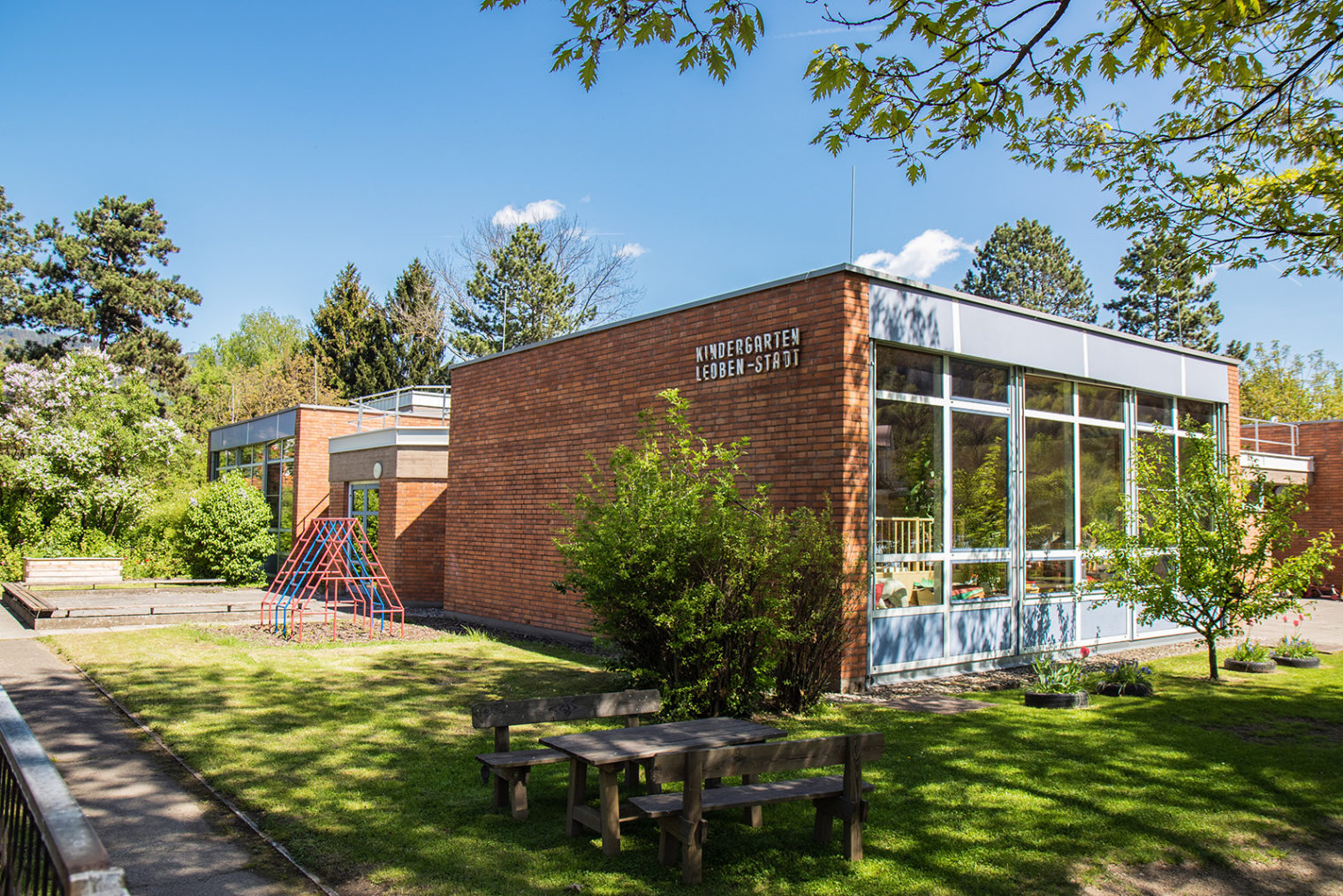 Außenaufnahme Kindergarten Leoben Stadt mit Klettergerüst und Sitzgelegenheit