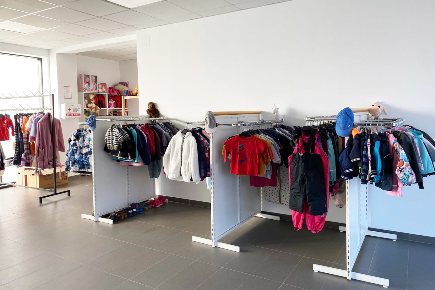 Innenansicht Sachspendenshop, Kinderbekleidung an Ständern