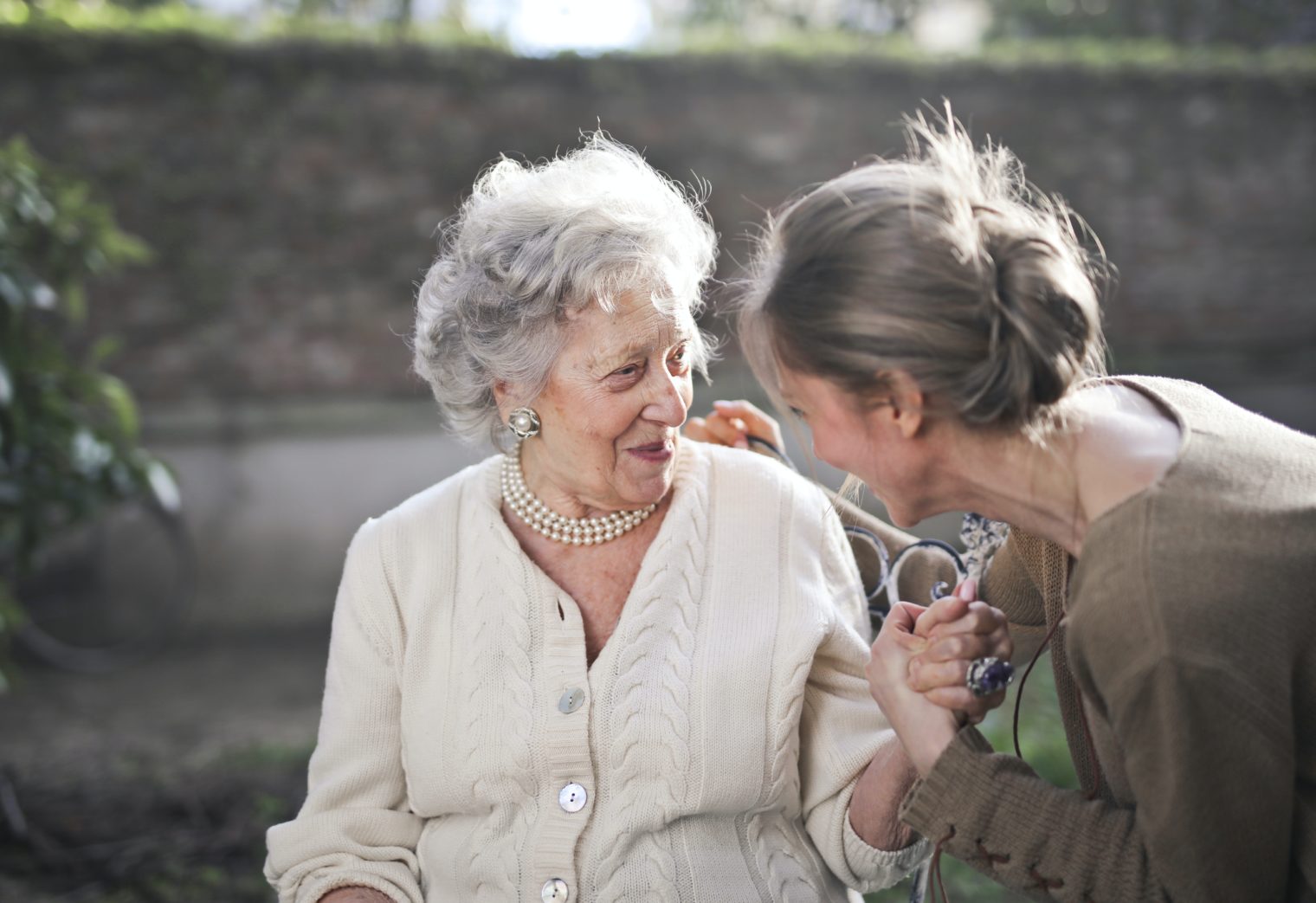 Junge Pflegerin unterhält sich mit älterer Seniorin