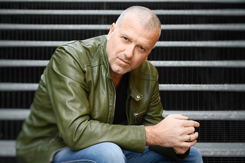 Autor Bernhard Aichner sitzt auf einer Treppe