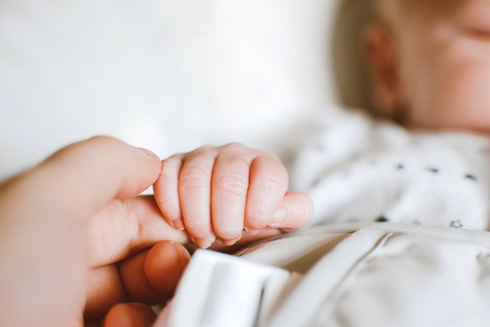 Baby hält die Hand eines Erwachsenen