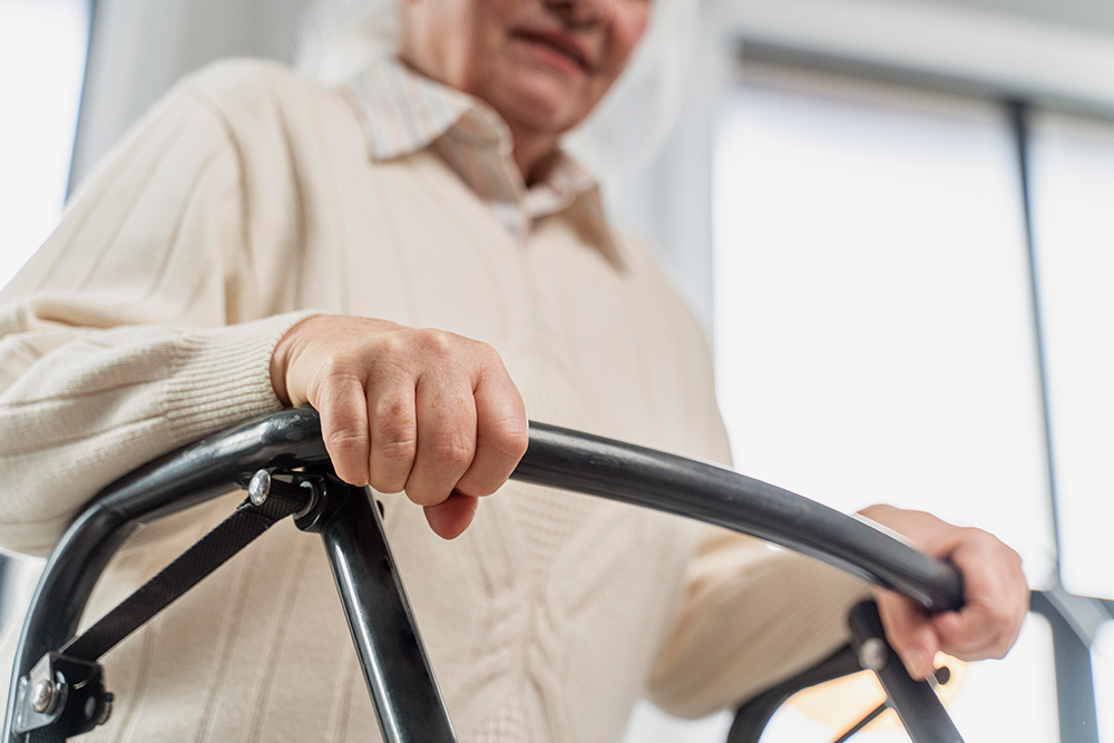 Ältere Person stützt sich auf Gehhilfe