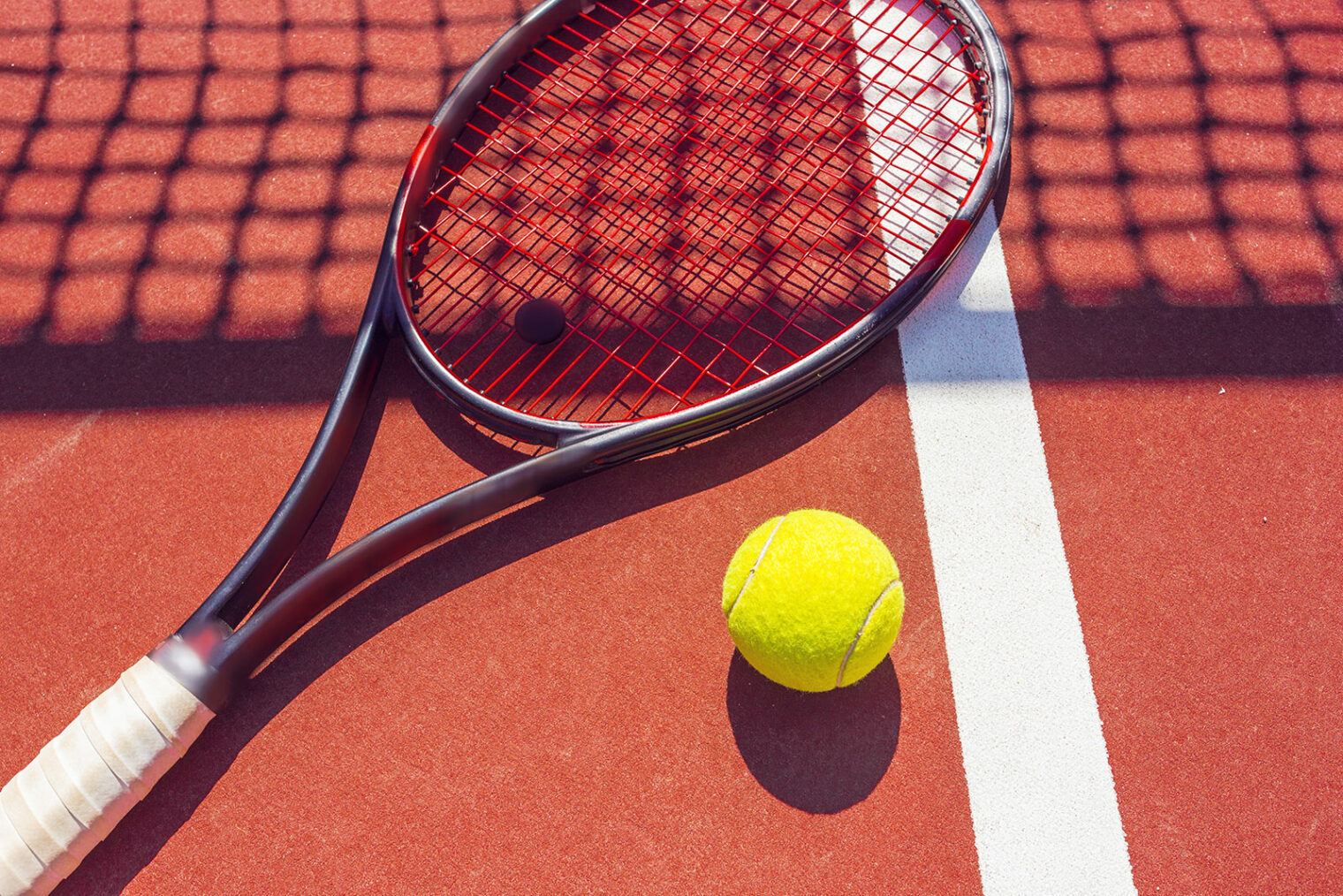 Tennisschläger und Ball liegen am Tennisplatz
