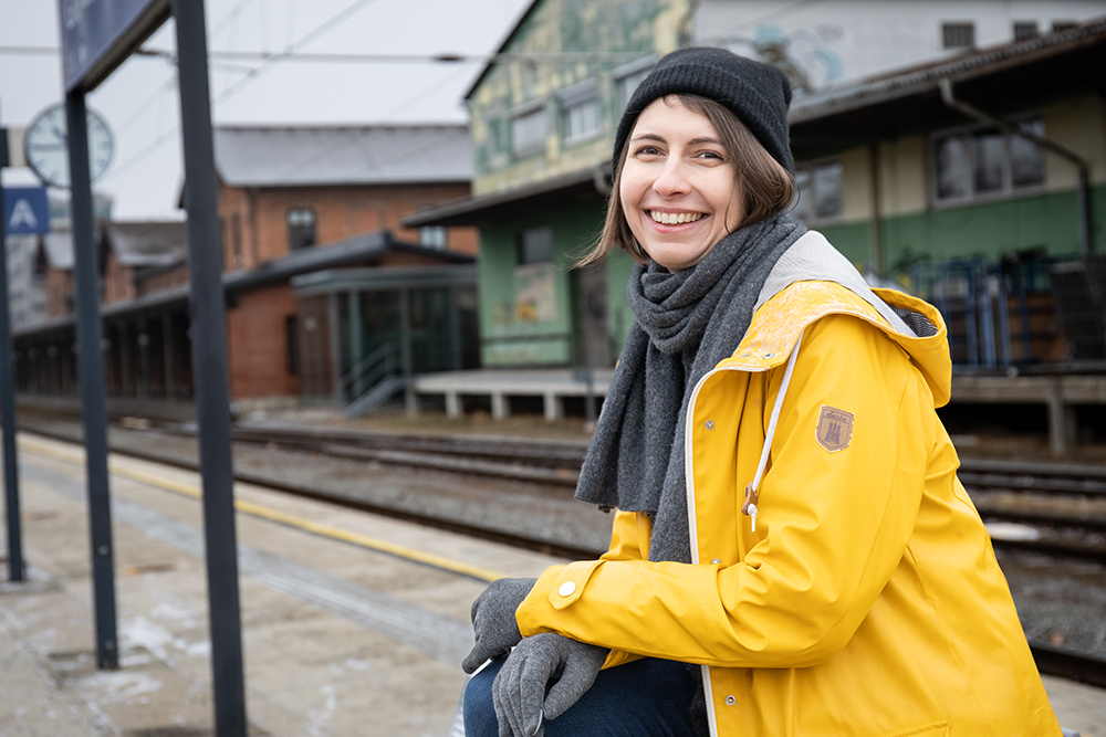 Autorin Chrissi Buchmasser sitzend am Bahnsteig