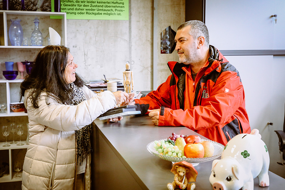 Mitarbeiter im ReUse-Shop mit Kundin