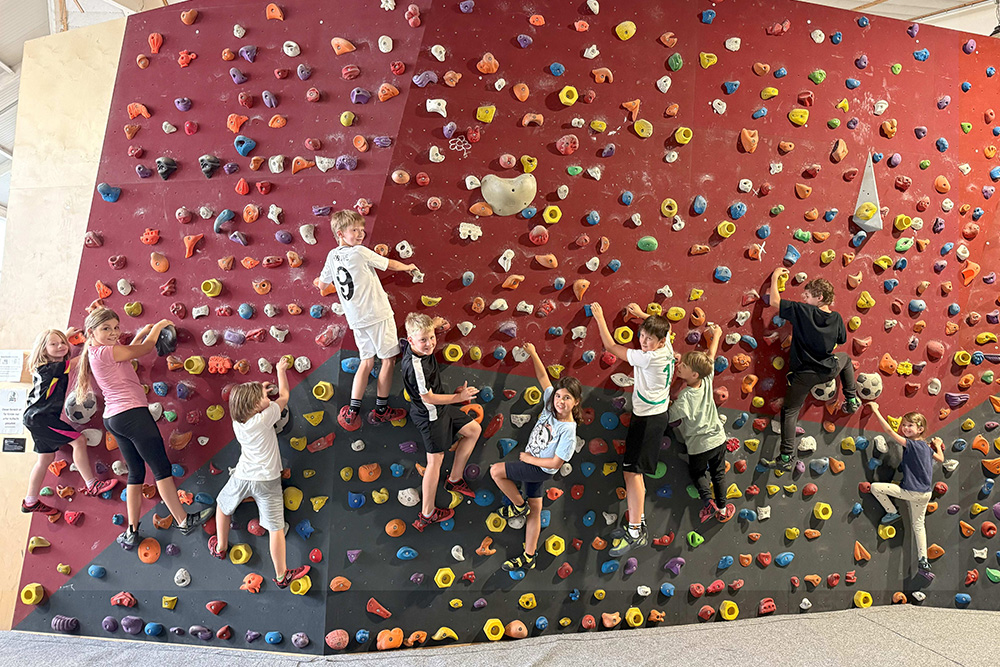 Kinder beim Bouldern an der Kletterwand in der Halle