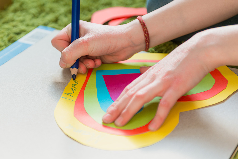 Mehrere Papierherzen übereinander geklebt, auf dem größten steht Mama geschrieben