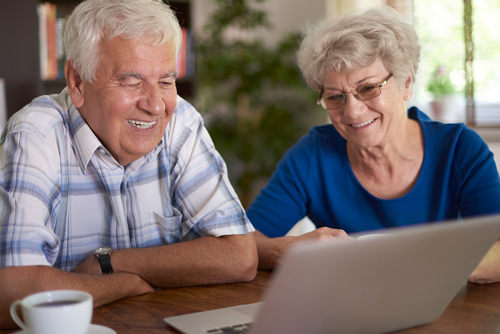 Senior:innen vor Laptop bei einer Tasse Kaffee