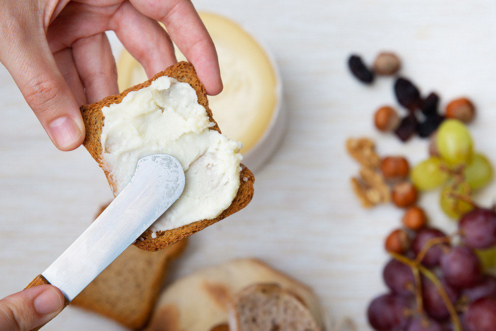 Detailaufnahme: Buttermesser bestreicht Brot mit Aufstrich