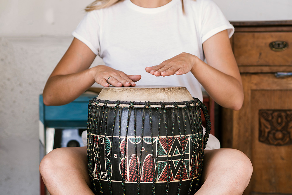 Weibliche Person trommelt auf der Djembe