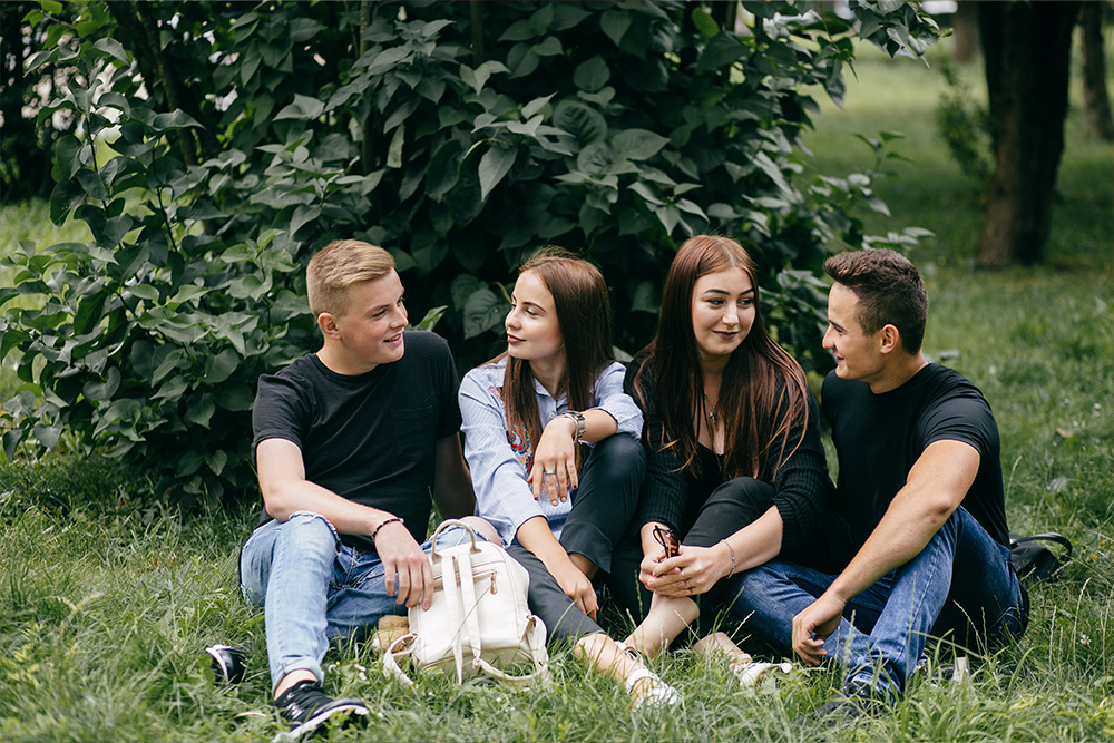 Symbolbild: vier Jugendliche, zwei Mädchen und zwei Buben, sitzend in der Wiese