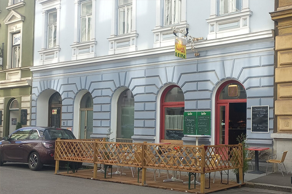 Pub Stehbeisl, Gebäudefassade, Außenansicht mit kleinem Gastgarten davor am Gehsteig und am Straßenrand