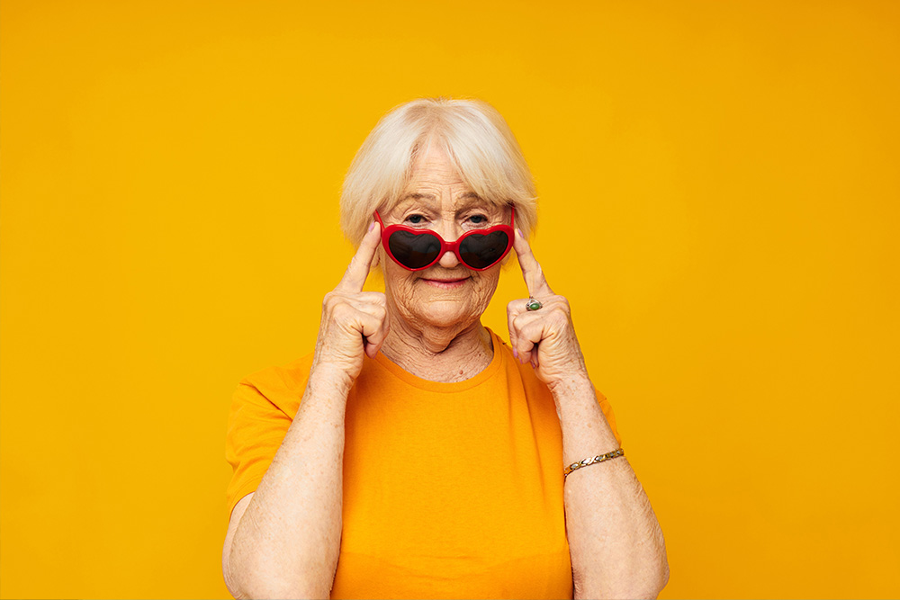 Seniorin guckt über Sonnenbrille mit Gläsern in Herzform