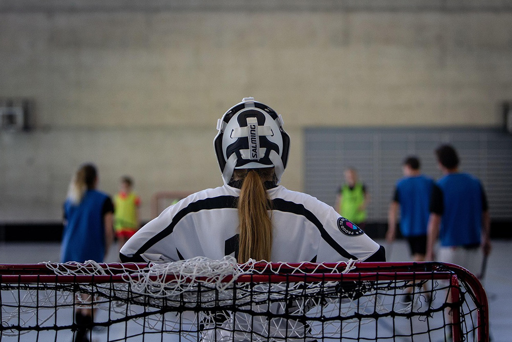 Mädchen mit Hockey-Schutzanzug steht im Tor