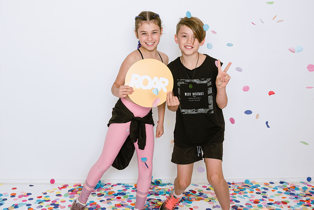 Kinder in Sportoutfit umgeben von Konfetti