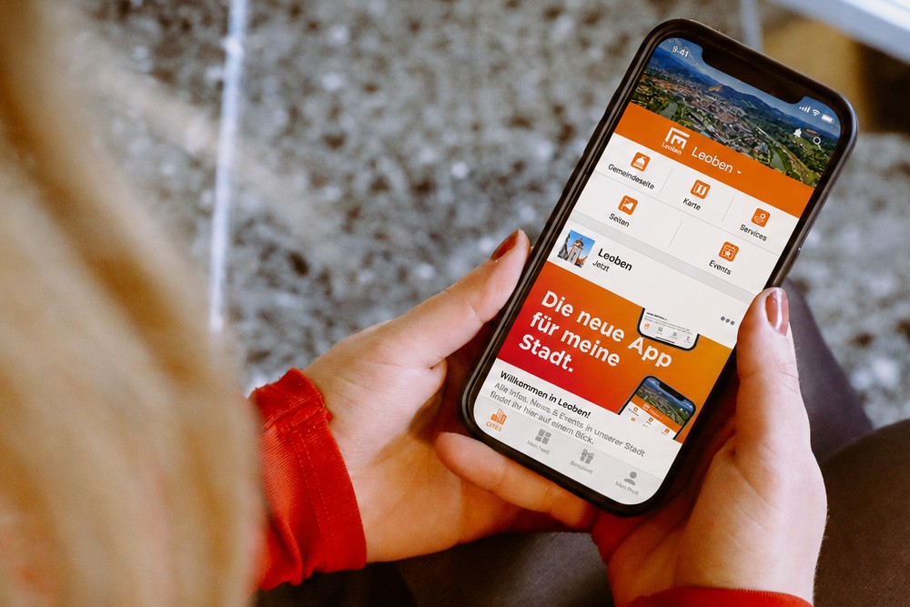Frau hält Smartphone mit Cities App